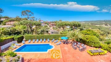 Piscine extérieure privée à la Villa Jaruco, dotée d'une terrasse en terre cuite bordée de transats rayés bleu et blanc et d'un coin repas sous un ciel bleu.