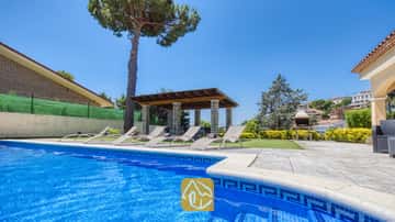 Piscine extérieure privée à la Villa Paris, dotée de bordures en carrelage bleu, de plusieurs chaises longues sur le patio, d'une pergola couverte et d'un barbecue en pierre en arrière-plan.