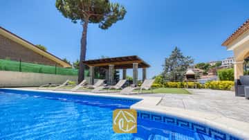 Piscine extérieure privée à la Villa Paris, dotée de bordures en carrelage bleu, de plusieurs chaises longues sur le patio, d'une pergola couverte et d'un barbecue en pierre en arrière-plan.