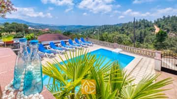 Piscine extérieure privée à la Villa Santa Maria avec des transats bleus sur la terrasse carrelée et collines verdoyantes au loin