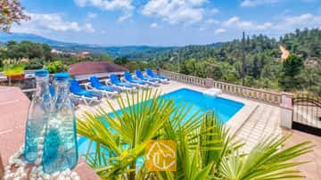 Piscine extérieure privée à la Villa Santa Maria avec des transats bleus sur la terrasse carrelée et collines verdoyantes au loin