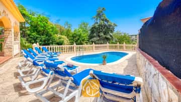 Piscine extérieure privée à la Villa Sarai, entourée de bains de soleil bleus, d'un patio en pierre et d'arbres verdoyants sous un ciel d'un bleu éclatant
