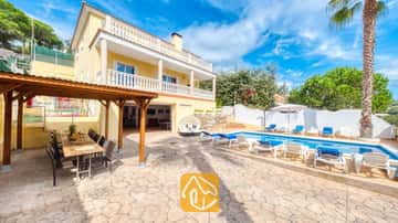 Piscine privée à la Villa Ashley aux eaux azur, agrémentée de transats blancs. Cette villa jaune se distingue par ses balcons à balustrades blanches et sa pergola en bois, idéale pour vos repas en plein air sur une terrasse en pierre.