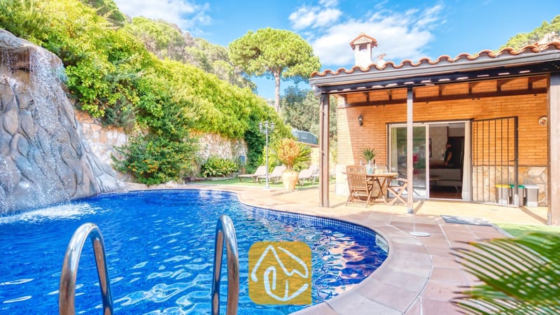 Piscine privée dotée d'une cascade en roches naturelles à la Villa Alba, mettant en valeur un patio extérieur en briques avec un mobilier de salle à manger en bois et un toit en tuiles.