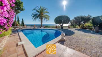 Piscine privée à la Villa Gabriella avec vue sur la mer, palmier et statue de Bouddha en pierre sur la terrasse carrelée.