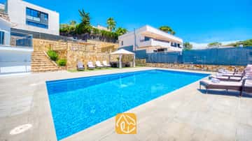 Piscine privée à la Villa SummerDream aux eaux d'un bleu éclatant, entourée de murs de soutènement en pierre, d'une terrasse carrelée et bordée de chaises longues.
