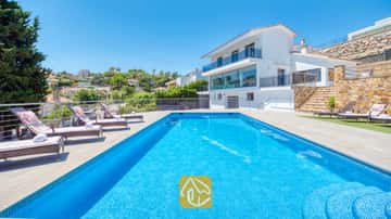 Piscine rectangulaire en mosaïque bleue et ses nombreux transats sur la terrasse pavée de la Villa SummerDream, en Espagne.