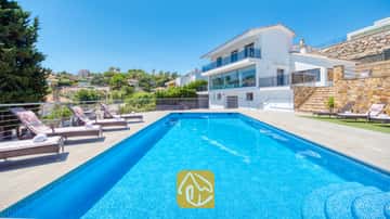 Piscine rectangulaire en mosaïque bleue et ses nombreux transats sur la terrasse pavée de la Villa SummerDream, en Espagne.