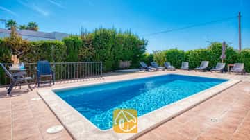 Piscine privée aux eaux bleues avec des chaises longues sur une terrasse pavée à la Villa Yara en Espagne.