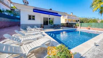 Piscine privée et transats blancs bordant la terrasse pavée de la Villa Zarita sous un ciel d'un bleu éclatant.