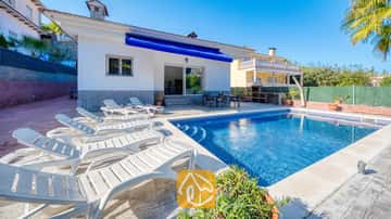 Piscine privée et transats blancs bordant la terrasse pavée de la Villa Zarita sous un ciel d'un bleu éclatant.