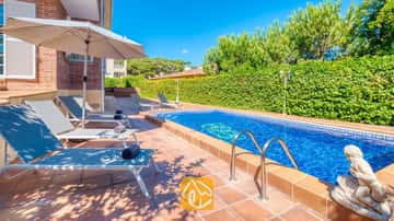 Piscine extérieure privée à la Villa Beyonce aux eaux bleues, dotée de mains courantes en métal et d'une statue en pierre, située à côté d'une rangée de transats gris sur une terrasse carrelée.