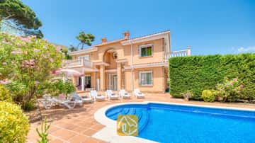Piscine privée et terrasse à la Villa Primavera, dotées de transats blancs, de sols en terre cuite et d'une façade couleur pêche sur deux étages sous un ciel bleu.