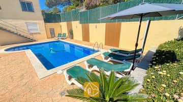 Piscine extérieure privée à la Villa Holiday, entourée de transats verts, d'un parasol sombre et d'un sol de patio en pierre.