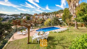 Piscine privée à la Villa Marysol, entourée d'une terrasse carrelée, d'une pelouse, d'une table à manger avec des chaises et de chaises longues, le tout sur fond de collines