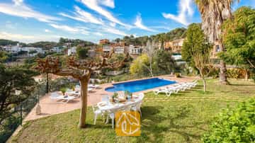 Piscine privée à la Villa Marysol, entourée d'une terrasse carrelée, d'une pelouse, d'une table à manger avec des chaises et de chaises longues, le tout sur fond de collines